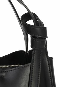 Sort læderhandtaske med et struktureret design, der har tekstureret syning og en snoet stropdetalje. Indersiden har en lynlåslomme.