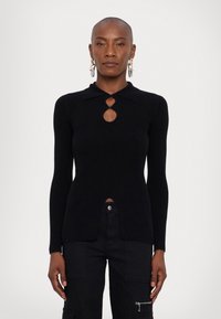 Μαύρο ραφιναρισμένο πλεκτό πουλόβερ με γιακά, με λεπτομέρεια ανοιχτού φρέντου και πλαϊνές σχισμές. Μακριά μανίκια και εφαρμοστή γραμμή. Συνδυάζεται με μαύρες cargo παντούφλες.