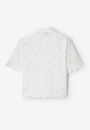 Witte blouse met korte mouwen, geschulpte randen en geborduurde oogjes bloemenpatronen, vanaf de achterkant getoond op een effen achtergrond.