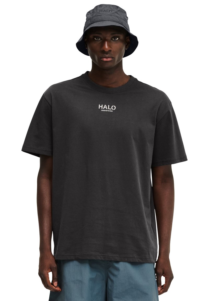 Sort bomulds-t-shirt med et lille hvidt logo på brystet og korte ærmer, parret med en mørkeblå bøttehat.