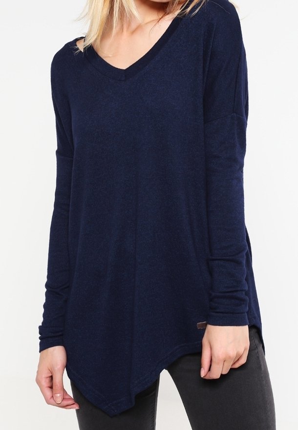 Haut à manches longues bleu marine avec un col en V et une longueur inégale. Fabriqué en tissu doux, il présente des fentes latérales et une petite étiquette de marque en bas.