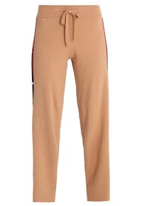 Beżowe spodnie dresowe wykonane z miękkiego materiału, z gumką w pasie i zwężanymi nogawkami, ozdobione czarnymi i bordowymi paskami po bokach dla kontrastu.
