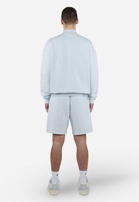 Lyseblå sweatshirt og matchende shorts, lavet af blødt materiale, med afslappet pasform og ribbede manchetter. Minimalistisk design uden mønstre.