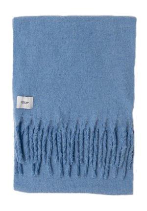 Hellblauer weicher Wollschal, gefaltet, mit fransigen Enden und einem kleinen weißen Markenetikett mit Text.