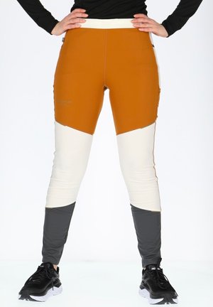 Tætsiddende leggings med orange, cremefarvede og grå paneler. Fremstillet af strækbart materiale med en glat overflade. Sorte sko fuldender looket.