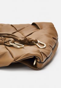 Brązowa skórzana torebka o pikowanym wzorze, z pozłacaną okuciami i plecionymi detalami, charakteryzująca się gładką teksturą i miękkim kształtem.