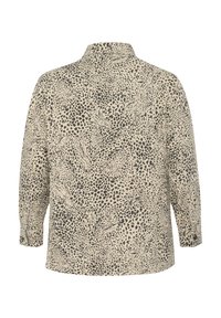 Beige long-sleeve shirt with a black abstract animal print. Features a collar and buttoned cuffs, providing a relaxed fit and textured design.