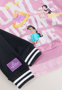 Sudadera rosa con gráficos de princesas Disney. Manga negra con rayas blancas y etiqueta morada. Material de algodón suave.