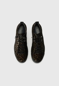 Black and brown leopard print sneakers with a textured upper, black laces, and “SUPER SOFT” embossed on the insoles, featuring a flexible rubber sole.