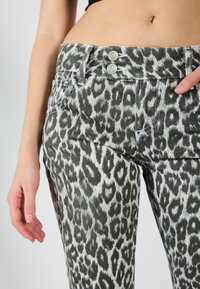 Løveprente jeans i grå og hvit denim, med to sølvknapper i midjen og en tettsittende silhuett for et skreddersydd utseende.