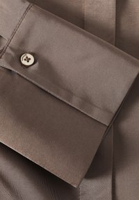 Brown satin shirt collar with a button detail. Smooth texture, folded design, and noticeable sheen. Classically tailored, modern aesthetic.