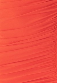 Sukienka z marszczeniem w żywym koralowym kolorze. Miękka faktura, luźny kształt z poziomymi plisami oraz marszczenia wzdłuż boku.