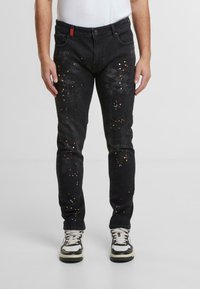 Czarne dżinsy denimowe z rozpryskami wielokolorowej farby, slim fit, pięć kieszeni, oraz kontrastowa czerwona pętla na pasku.