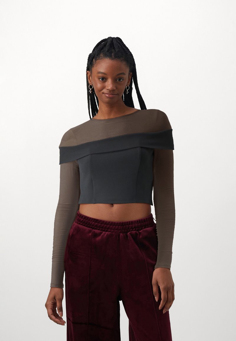 Crop top med svart tettsittende kropp, brune gjennomsiktige lange ermer, og off-the-shoulder design; sammen med maroon pløse bukser.