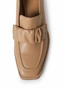 Mocasines de cuero beige con diseño de punta cuadrada, que presentan un destacado lazo trenzado y detalles de costura a lo largo de los lados.