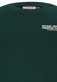 Zielona bawełniana koszulka z okrągłym dekoltem. Z przodu znajduje się biały tekst: "RETOUR JEANS ESSENTIAL Pro TO ZACZYNA SIĘ Z."