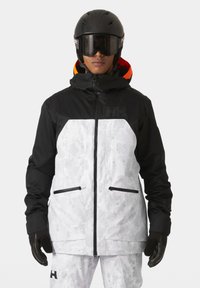 Skijacke in Schwarz und Weiß mit geometrischem Muster, ausgestattet mit einer Kapuze, Reißverschlusstaschen und moderner Passform. Mattes Finish mit kontrastierenden Akzenten.