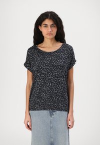 Black and gray leopard print t-shirt, short sleeves, rounded neckline, soft fabric. Worn with a light blue denim skirt, slight sheen.