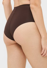 Brown high-waisted underwear with a smooth texture and minimal seam detailing, designed for a comfortable fit.