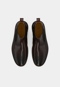 Zapatos marrones de piel sin cordones con paneles laterales elásticos, puntera redondeada y acentos en el talón de color marrón contrastante. Textura suave y acabado pulido.