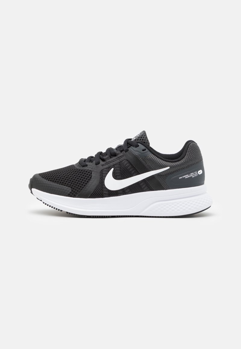 Zwart sportief schoen met mesh bovenwerk, wit Nike swoosh-logo en een witte midzool. Heeft een gestructureerde hiel en een patroonzool.