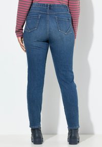 Jeans i mörkblå denim med tapered fit, med en bred elastisk midja, bakfickor och en mjuk yta.