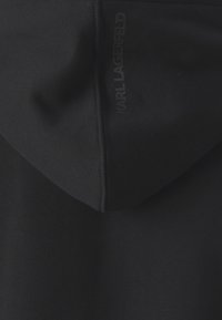 Svart hettegenser med en myk tekstur. Har hette og sømdetaljer. Lite, preget "KARL LAGERFELD"-logo på baksiden.