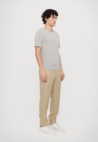 Gray short-sleeve shirt with a round neck, paired with beige linen trousers and white sneakers, featuring subtle texture and relaxed fit.