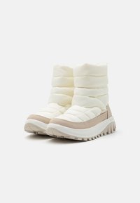 Hvite puffer-stil ankelstøvler med en beige såle, med quiltet tekstur, en rund tå, og en robust yttersåle med godt feste.