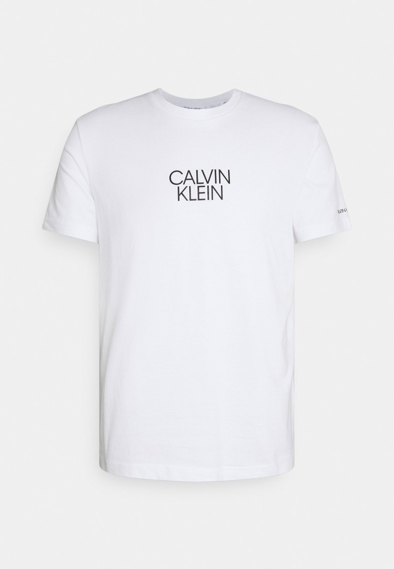 Camiseta de algodón blanca con cuello redondo y mangas cortas, con un logo negro de "CALVIN KLEIN" centrado en el pecho.