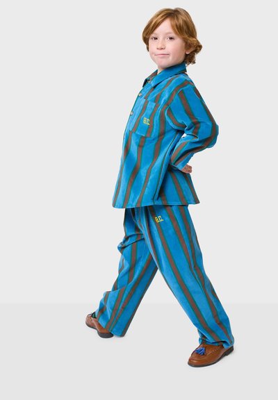 Prugasta plava i smeđa tkanina, odjeća s košuljom na dugmad i odgovarajućim hlačama, koja ima džep na prsima i vez "B.C.".