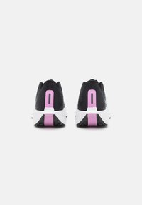 Scarpe da ginnastica nere con sopra strutturato, intersuole bianche e dettagli sul tallone rosa. Tra le caratteristiche ci sono un design posteriore distintivo e suole in gomma.