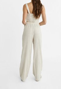 Ensemble deux pièces rayé comprenant un crop top ajusté à larges bretelles et un pantalon ample taille haute en tissu léger et texturé.