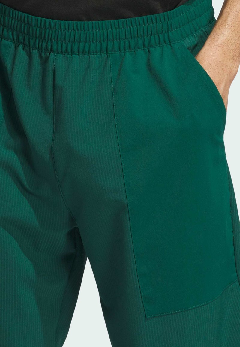 Grüne, leichte Hose mit gerippter Textur, elastischem Bund und großer Seitenasche. Geeignet für Freizeit- und Sportbekleidung.
