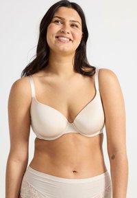 Lys beige bh med glatte, formede skåle og justerbare stropper. Materialet har en blød tekstur, der giver et sømløst udseende.