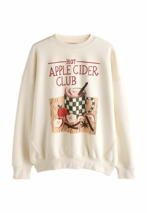 Flødefarvet sweatshirt med teksten "Hot Apple Cider Club" og illustration af et ternet krus, skivede æbler og krydderier på en træoverflade.