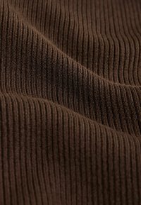 Braun geripptes Gewebe mit einer weichen Textur, das vertikale Linien aufweist und eine leicht dehnbare Qualität hat. Eine Nahaufnahme hebt die Webdetails hervor.