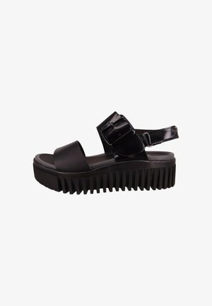 Sandalias de plataforma negras con suela gruesa, material superior brillante, correa ancha y hebilla ajustable. Suela texturizada con estrías verticales.