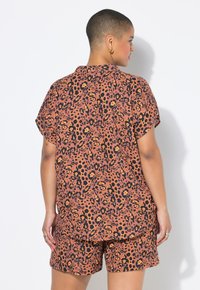 Korte mouwen top en short set in roestkleur met zwart en gouden luipaardprint. Lichtgewicht stof met een relaxte pasvorm en een afgeronde zoom.