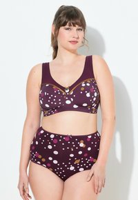 Lila Unterwäsche-Set mit einem gepunkteten Muster in Weiß, Pink und Braun. Der BH hat breite Träger und eine kleine Schleifenakzent in der Mitte. Hochgeschnittene Unterhose.