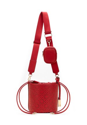 Rote Bucket Bag mit floralem Cutout-Muster, breitem verstellbarem Schultergurt und kleinem Reißverschlussbeutel, der am Gurt befestigt ist.