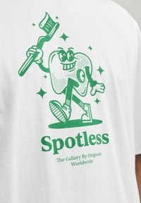 Tricou alb cu un dinte verde, în stil cartoon, care ține o periuță de dinți, înconjurat de stele strălucitoare, cu inscripția "Impecabil" imprimată dedesubt, în verde.
