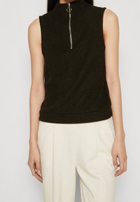 Dunkelgrünes ärmelloses Stricktop mit hohem Kragen und Front-Reißverschluss, ausgestattet mit einem engen Saum und dezent gerippter Struktur.