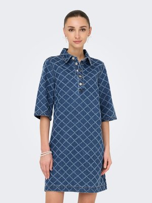Donna che indossa un vestito di jeans blu con motivo a quadri, colletto abbottonato, maniche al gomito e braccialetti di perle a un polso.