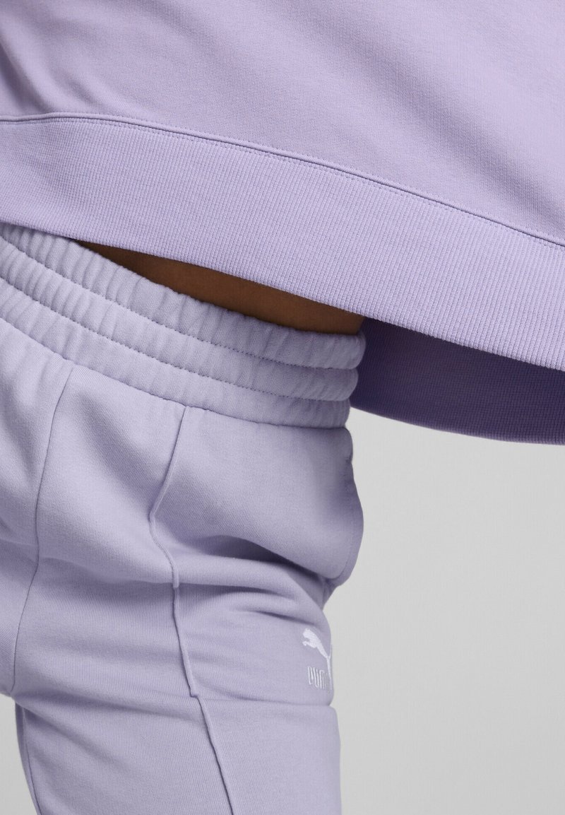 Sweat-shirt lilas avec ourlet côtelé, assorti à un pantalon taille élastique à cordon de serrage et logo brodé sur la cuisse.