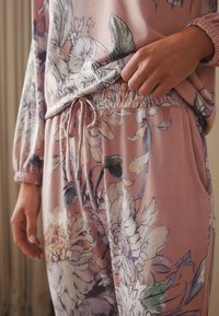 Ensemble de vêtements d'intérieur rose clair avec des motifs floraux violets et verts, doté d'une ceinture élastique et d'un cordon de serrage, fabriqué en tissu doux.