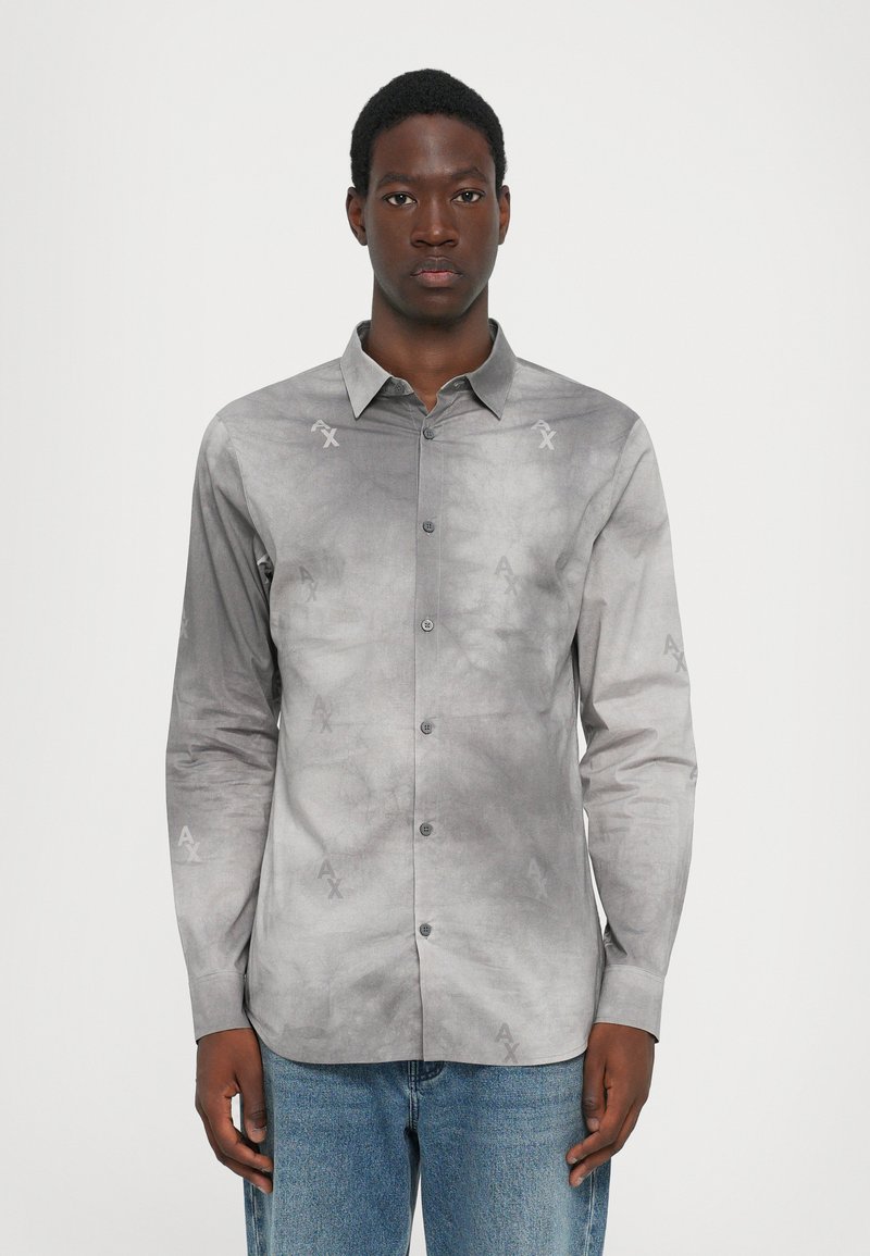 Grå skjorte med strukturert finish, med et subtilt logomønster og lange ermer. Kombinert med blå denimjeans.