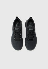 Une paire de chaussures de sport larges Skechers Flex-Lite noires avec des dessus en mesh et des lacets, vue de dessus sur un fond blanc.