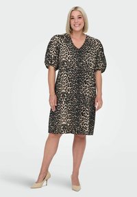 Klänning med leopardtryck, V-ringning, korta pösiga ärmar och en lös passform. Tillverkad av lätt tyg. Matchas med beige högklackade skor.