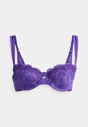 Soutien-gorge en dentelle violette avec motif floral, bonnets rembourrés, bretelles réglables et un détail central décoratif. Tissu lisse avec des accents texturés.